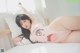 A woman in a pink bodysuit laying on a bed.